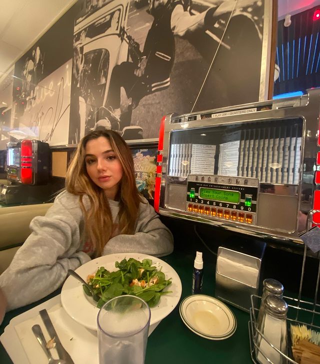 Alexa Nisenson posing with the food in a restaurants